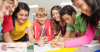 A group of middle school students stand around a table looking at open notebooks and smiling. Two students are writing with pencils in the notebook in the middle.