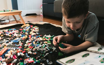 A young boy follows a guide to construct a model with Legos.