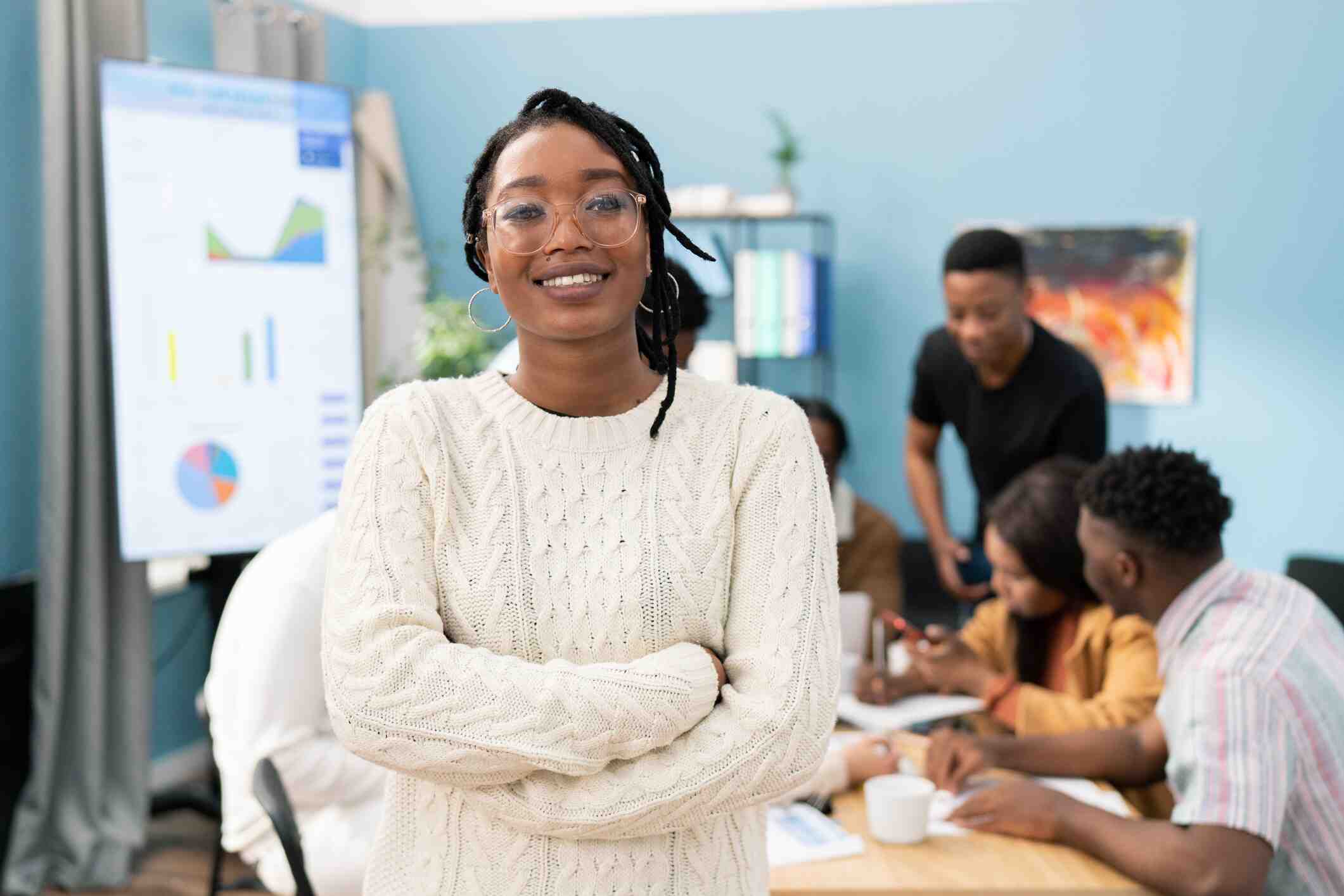 A black woman stands as her colleagues look on.