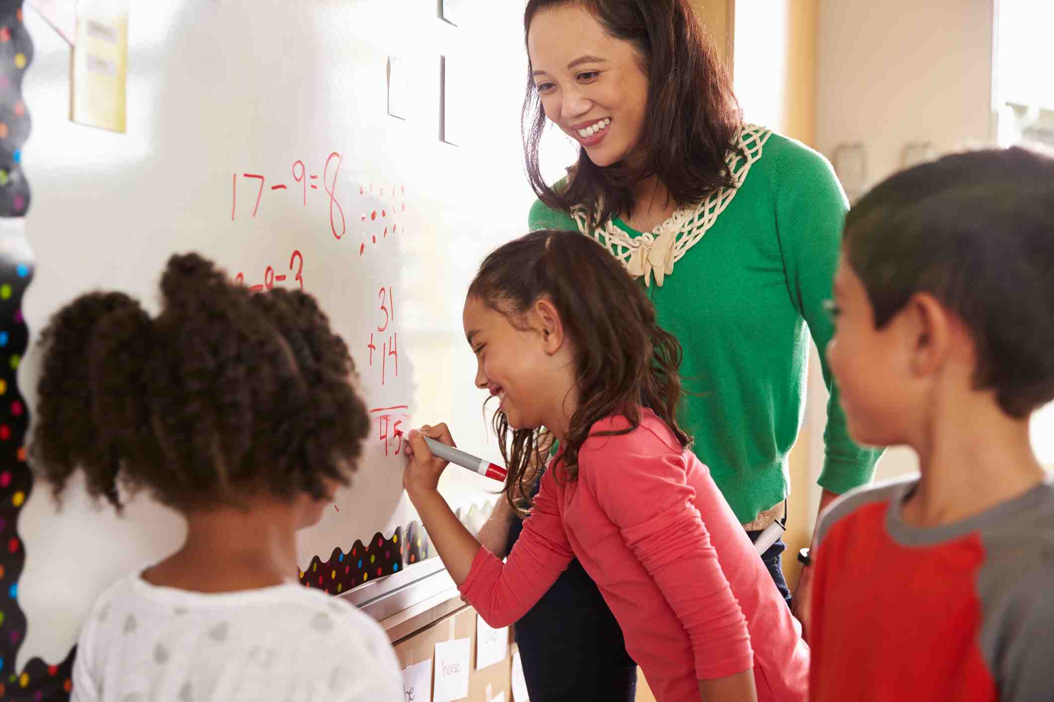 A teacher at the board doing math with her students.