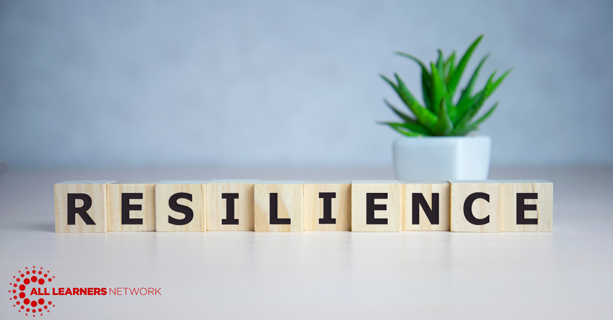 White table has a succulent in the background and the foreground has wooden letter blocks that spell resilience.